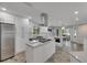 Modern kitchen with white shaker cabinets, a large island with a smooth cooktop, and stainless steel appliances at 6613 Seabird Way, Apollo Beach, FL 33572