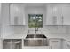 Modern kitchen with stainless steel farmhouse sink, white shaker cabinets, and quartz countertops at 6613 Seabird Way, Apollo Beach, FL 33572