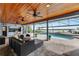 Covered patio with outdoor kitchen, ceiling fans, pool, and waterfront views at 6613 Seabird Way, Apollo Beach, FL 33572