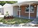 Landscaped front yard with a covered porch and brick exterior at 8391 76Th Ave, Seminole, FL 33777