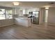 Open-concept kitchen and living area with white cabinets, stainless steel appliances, and wood-look flooring at 8391 76Th Ave, Seminole, FL 33777