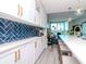 Modern white kitchen with blue tile backsplash, gold fixtures, and bar seating at 912 Channelside Dr # 2412, Tampa, FL 33602