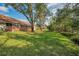 Expansive backyard featuring a screened porch, mature trees, and lush green grass at 1055 Riverside Ridge Rd, Tarpon Springs, FL 34688