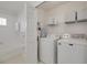 Laundry room with a washer and dryer, shelving, and a doorway to a bathtub at 13336 Ashbark Ct, Riverview, FL 33579