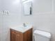 Bathroom with white tile, wood vanity, and white sink and toilet at 1536 77Th N Ave, St Petersburg, FL 33702