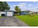 A well-kept blue house features a lush lawn, driveway, and tropical landscaping at 2461 61St N Ln, St Petersburg, FL 33710