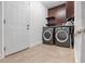 Laundry room with dark wood cabinetry, front-loading washer and dryer, and tile floor at 2461 61St N Ln, St Petersburg, FL 33710