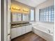 Well-lit bathroom featuring a double vanity, a large soaking tub, and wood-look floors at 1333 Misty Greens Dr, Sun City Center, FL 33573