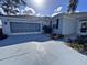 Angle view of a well-maintained home with a screened garage, featuring a long driveway and neat landscaping at 1333 Misty Greens Dr, Sun City Center, FL 33573