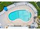 Aerial view of a kidney-shaped pool with lounge chairs, umbrellas, and a wooden deck at 1700 Cove Ii Pl # 310, Sarasota, FL 34242