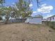 Backyard view of a light blue single-story home with a fenced yard and trees at 1708 E Poinsettia Ave, Tampa, FL 33612