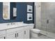 Modern bathroom featuring blue accent wall, vanity with sink, toilet, and sleek glass-enclosed shower with tile surround at 17390 Moonflower Dr # 102, Venice, FL 34293