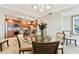 Open-concept dining area with glass table, modern chandelier, and view of the kitchen at 4 Belleview Blvd # 801, Belleair, FL 33756