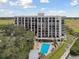 Condo building with a pool, surrounded by trees and grass, near a body of water at 4 Belleview Blvd # 801, Belleair, FL 33756