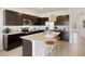Contemporary kitchen featuring dark cabinets, stainless steel appliances, and a large island at 5047 Captain Davis Dr, Wimauma, FL 33598