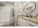 Bathroom with white vanity, granite countertop, and a bathtub with a striped curtain at 6937 Exeter Park Pl, Apollo Beach, FL 33572