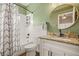 Bathroom with green walls, white vanity, granite countertop, and patterned shower curtain at 6937 Exeter Park Pl, Apollo Beach, FL 33572