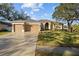 Charming single-story home featuring a well-manicured lawn, three-car garage, and beautiful arched entryway at 10101 Paddock Oaks Dr, Riverview, FL 33569
