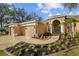 Lovely front yard landscaping leads up to this tan home with a three car garage and covered porch entry at 10101 Paddock Oaks Dr, Riverview, FL 33569