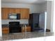 Modern kitchen with dark granite countertops, black appliances, and wood cabinets at 10737 Keys Gate Dr, Riverview, FL 33579
