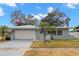 Ranch style home with a white garage door and palm trees at 1816 Woodridge Dr, Clearwater, FL 33756