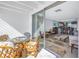 Balcony with a glass-top table and wicker chairs, offering a view of the living room and ocean at 7000 Beach Plz # 706, St Pete Beach, FL 33706