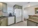 Kitchen showcasing the white refrigerator, dishwasher, and light green cabinets, with tiled backsplash at 7000 Beach Plz # 706, St Pete Beach, FL 33706