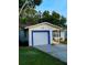 House exterior featuring a white garage door, blue accents, and a well-manicured lawn at 7471 35Th N St, Pinellas Park, FL 33781