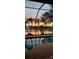 Screened-in pool reflects sunset, palm trees, and lake at 1160 Darlington Oak Ne Dr, St Petersburg, FL 33703