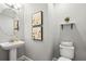 Charming half bath with pedestal sink, decorative wall art, and classic toilet creating a simple aesthetic at 2378 Whittler Br, Odessa, FL 33556