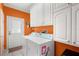 Laundry room with white cabinets, washer, dryer, and orange walls at 37226 Lakewood Dr, Zephyrhills, FL 33542