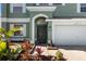 This property features a front entrance that has an arched doorway, a two-car garage, and tropical landscaping at 11351 Callaway Pond Dr, Riverview, FL 33579