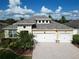 Two-story house with a light-yellow facade, white garage doors, and landscaping at 12316 Juniper Field Ct, Riverview, FL 33579