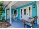 Charming front porch with rocking chairs, columns, and a vibrant turquoise facade at 2993 W Vina Del Mar Blvd, St Pete Beach, FL 33706