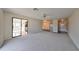 Living room with gray carpet, sliding glass door to a sunroom, and view of the kitchen at 2701 Lancaster Dr, Sun City Center, FL 33573