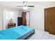 Bedroom with teal bedding, ceiling fan, and open doorway at 5316 Buttonwood Dr, New Port Richey, FL 34652