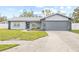 Front exterior of a single-story home with a gray facade, attached garage, and landscaped yard at 6090 114Th N Ter, Pinellas Park, FL 33782