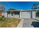 One-story house with front yard, driveway, and trees in the background at 9316 Gray Fox Ln, Port Richey, FL 34668