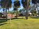 View of Cove Cay Clubhouse and sign with palm trees and manicured lawn at 2700 Cove Cay Dr # 2F, Clearwater, FL 33760
