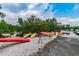 Colorful kayaks are arranged near the water's edge, with lush greenery in the background, under a partly cloudy sky at 2700 Cove Cay Dr # 2F, Clearwater, FL 33760