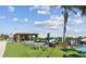 Outdoor dining area with tables and chairs, shade structures, a blue sofa, and a palm tree on green turf at 2700 Cove Cay Dr # 2F, Clearwater, FL 33760