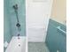 Bathroom with teal tile, bathtub, and white door at 323 W Hanna Ave, Tampa, FL 33604