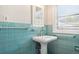Bathroom with teal tile, white pedestal sink, and window at 323 W Hanna Ave, Tampa, FL 33604