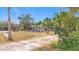 Front view of a house with palm trees, a dirt driveway, and some cacti at 569 Dixie Hwy, Tarpon Springs, FL 34689