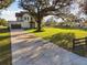 Driveway view of a two-story home with a dark gray garage, trees, and fencing at 6303 Barton Rd, Plant City, FL 33565