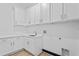 Well-lit laundry room area featuring white cabinetry, modern hardware, and quartz countertops at 6303 Barton Rd, Plant City, FL 33565