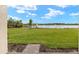 Expansive back yard with lush green grass and a serene lake view under a clear sky at 11726 Renaissance Blvd, Venice, FL 34293