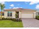 Charming single-story home featuring a tile roof, attached garage, and beautiful landscaping at 11726 Renaissance Blvd, Venice, FL 34293