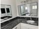 Double vanity with a gray granite countertop, modern lighting, and large mirrors in a bright bathroom at 12186 Lamont Dr, Spring Hill, FL 34608