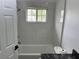 A tub with white tiled walls is featured in a bathroom with a window and a modern shower head at 12186 Lamont Dr, Spring Hill, FL 34608